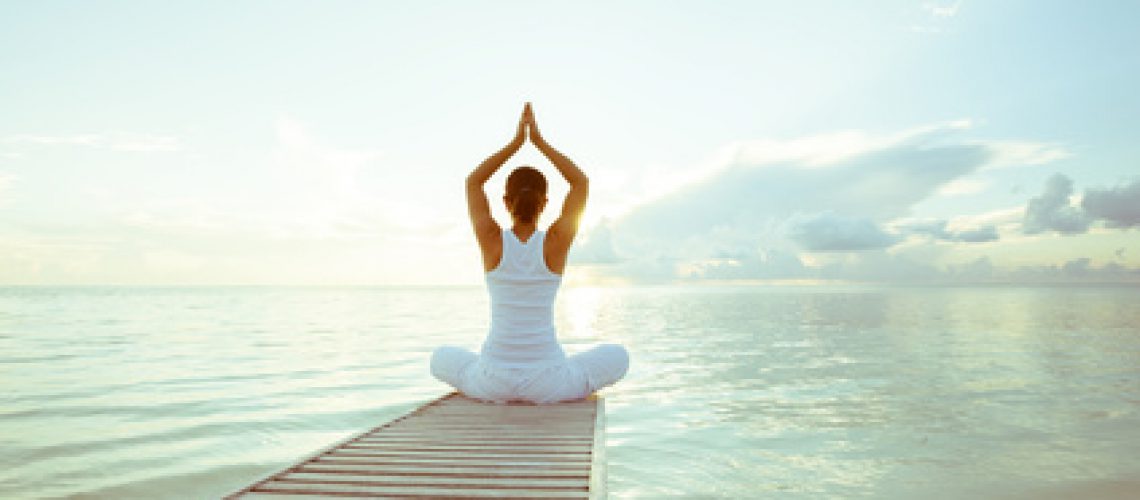 Caucasian woman practicing yoga at seashore